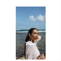 a woman is posing in front of the ocean